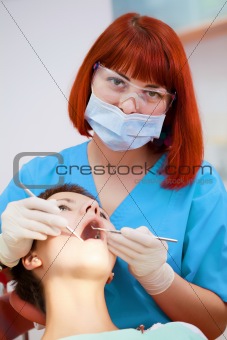 Image of young lady with dentist over her checking oral cavity 
