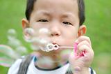 asian kid blowing soap bubble
