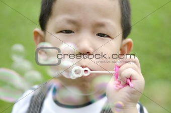 asian kid blowing soap bubble