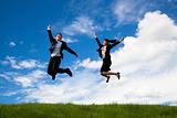 Happy Businessman and businesswoman jumping on a green meadow