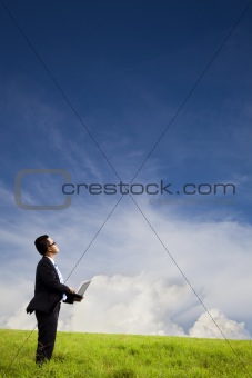 Businessman holding computer and watching the cloud