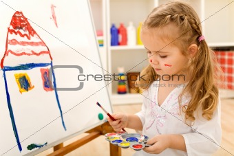Little artist girl painting on large paper canvas