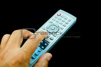 Remote control in hand, isolated on black background.