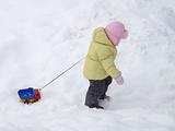A child carries toy car in the snow 