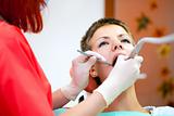 Image of young lady with dentist over her checking oral cavity 
