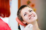 Image of young lady with dentist over her checking oral cavity 
