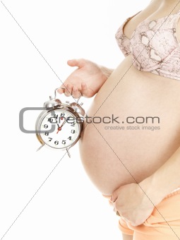 Portrait of young pregnant woman holding an alarm clock