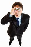 Shocked young businessman looking through binoculars
