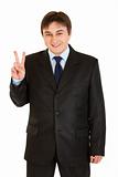 Happy young businessman showing victory gesture
