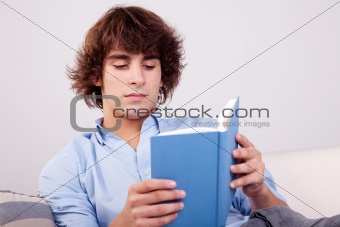 man seated reading a book on couch