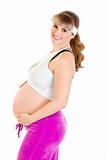 Smiling beautiful pregnant woman in sportswear holding her belly

