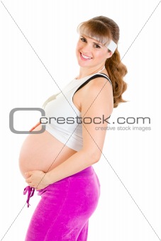 Smiling beautiful pregnant woman in sportswear holding her belly
