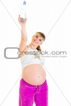 Smiling beautiful pregnant woman in sportswear holding bottle of pure water
