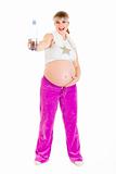 Happy beautiful pregnant woman in sportswear holding bottle of pure water
