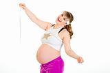 Pleased beautiful pregnant woman holding measure tape in hands
