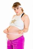 Frustrated pregnant woman measuring her belly
