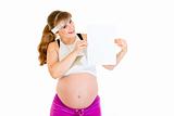 Smiling beautiful pregnant woman holding empty white  paper over her head
