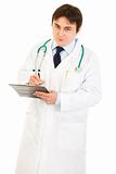 Smiling doctor  with stethoscope making notes in medical chart
