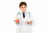 Confident  medical doctor with tablets in one hand and apple in other
