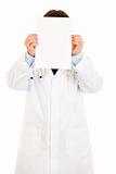 Doctor holding empty white  paper in front of her face
