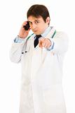 Medical doctor talking on mobile phone and pointing finger at you
