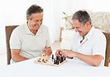 Senior men playing chess at home