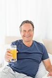 Retired man looking at the camera while he is drinking orange juice