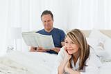 Woman smiling while her husband is reading