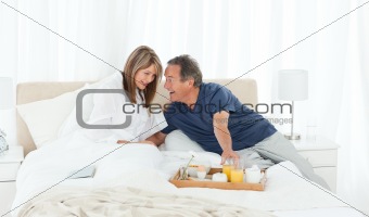 Lovely couple having breakfast in their bed 