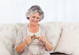 Senior woman knitting on her sofa