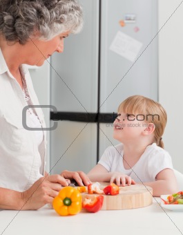 Little girl looking at her grandmother who is cooking 