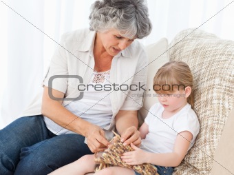 Grandmother helping her little girl to knit
