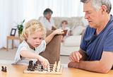 Young boy playing chess with his grandfather