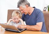Lovely boy and his grandfather looking at their laptop 