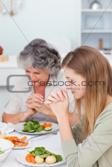 Woman and her mother praying at the table