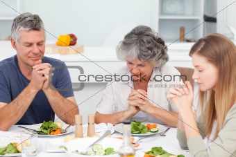 Adorable family praying at the table