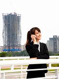 Happy asian business woman talking on the phone and office building background