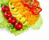 Mix of fresh vegetables from a colored paprika on leaves of green salad on a white background