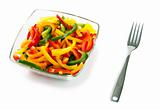 Mix of fresh vegetables from a color paprika in a glass plate on a white background with a plug
