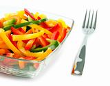 Mix of fresh vegetables from a color paprika in a glass plate on a white background with a plug