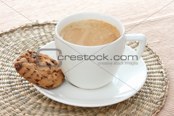 Chocolate chip cookie on saucer with coffee