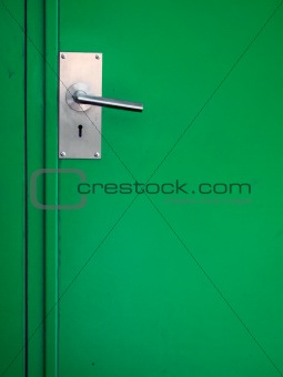 Metal door handle on green