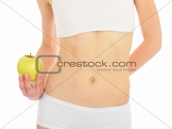 woman with beautiful body holding an apple near the slim waist. 