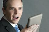 Businessman Looks At Tablet With Pleased Surprise