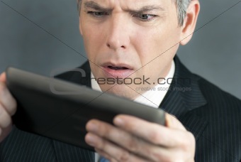 Worried Businessman Looks At Tablet