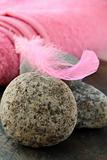pink feather on the stones and pink towel in the background