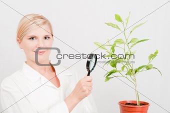 pretty female biology scientist with green plant