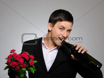 Handsome romantic young man holding rose flower and vine bottle 