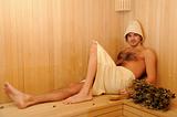 Young handsome man in a towel relaxing in a russian wooden sauna