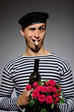 Funny romantic sailor man opening bottle and holding rose flower
